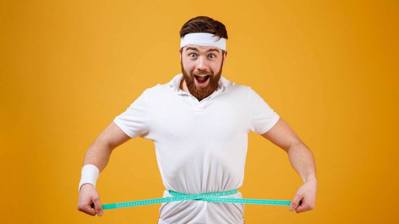 happy-bearded-fitness-man-measuring-his-waist-with-tape_171337-15817.jpg